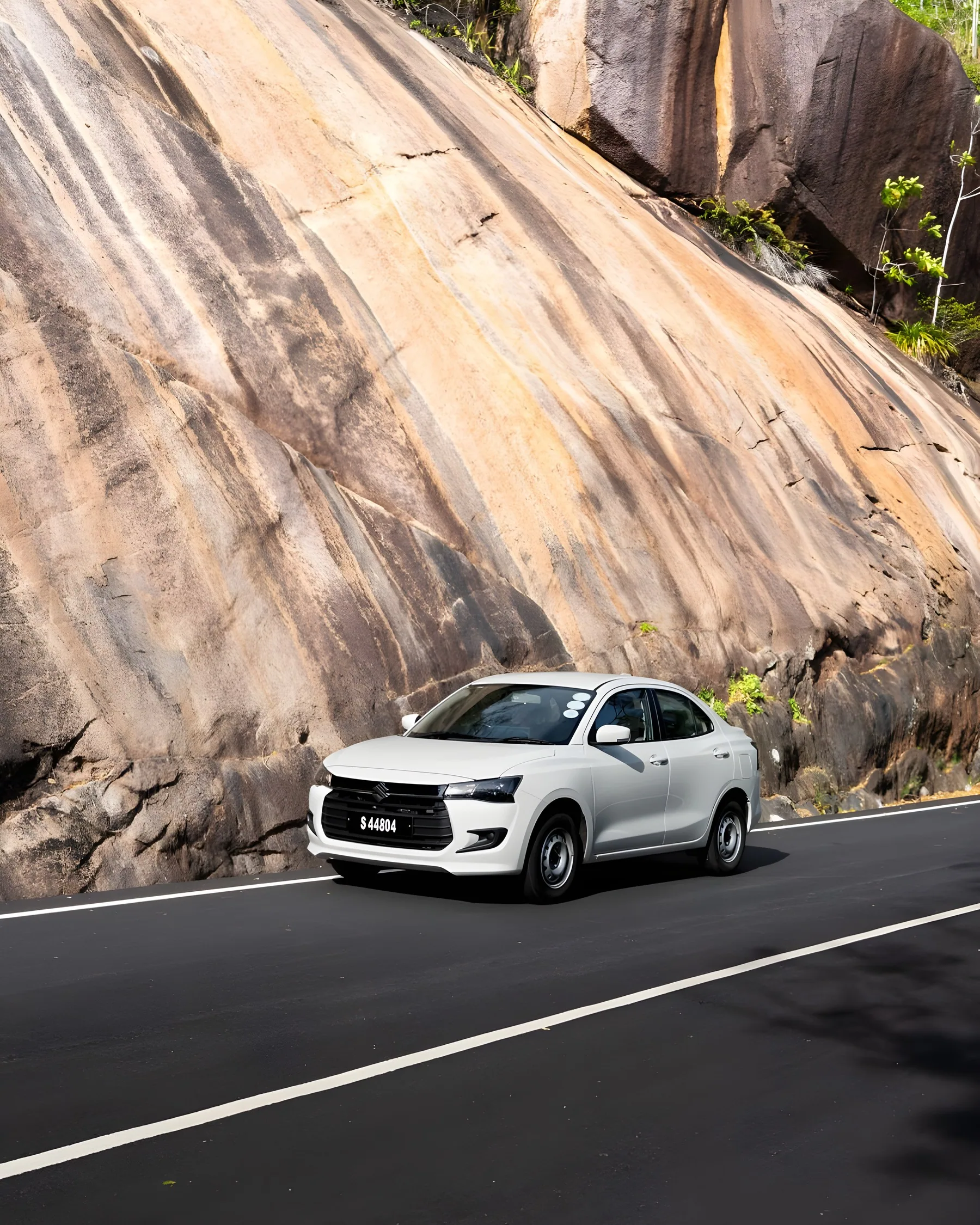 Suzuki Dzire in front of a towering granite rock face